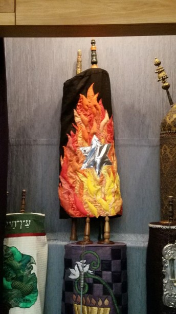 Temple Israel, Dayton, OH's České Budějovice scroll (MST #313) . Temple Israel’s Conformation Class commissioned the cover with a star on a black background which is unconsumed by the flames surrounding it. The cover was handmade by Temple Israel President, Carol Finley.